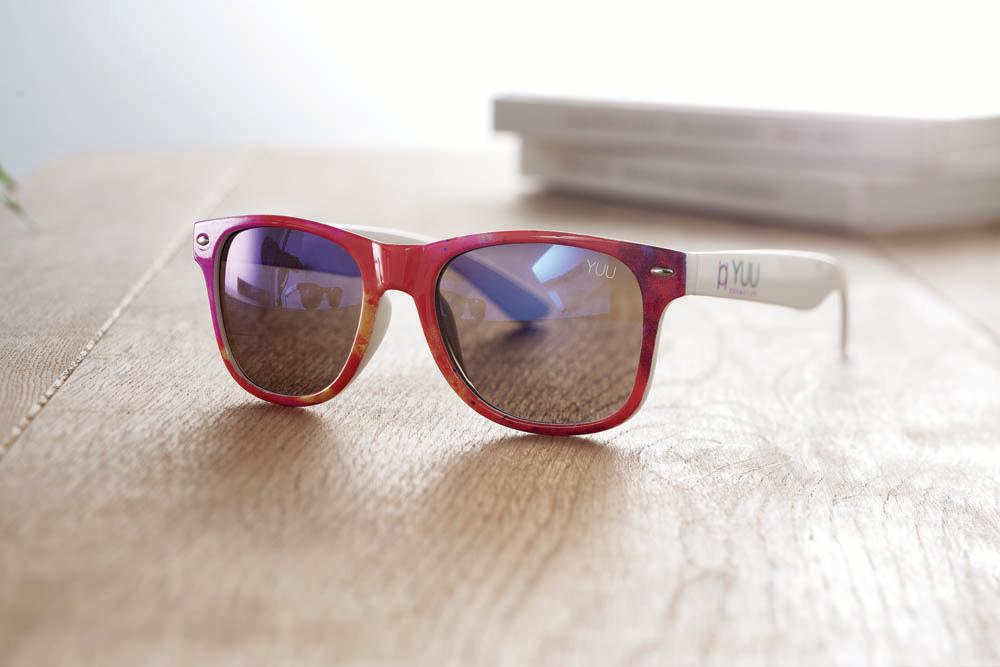 Solglasögon Tuv – exempel i miljö med tryck Solglasögon Tuv på bord med fullfärgstryckt båge i rosa/lila och vit skalm med logotyptryck (miljöbild)