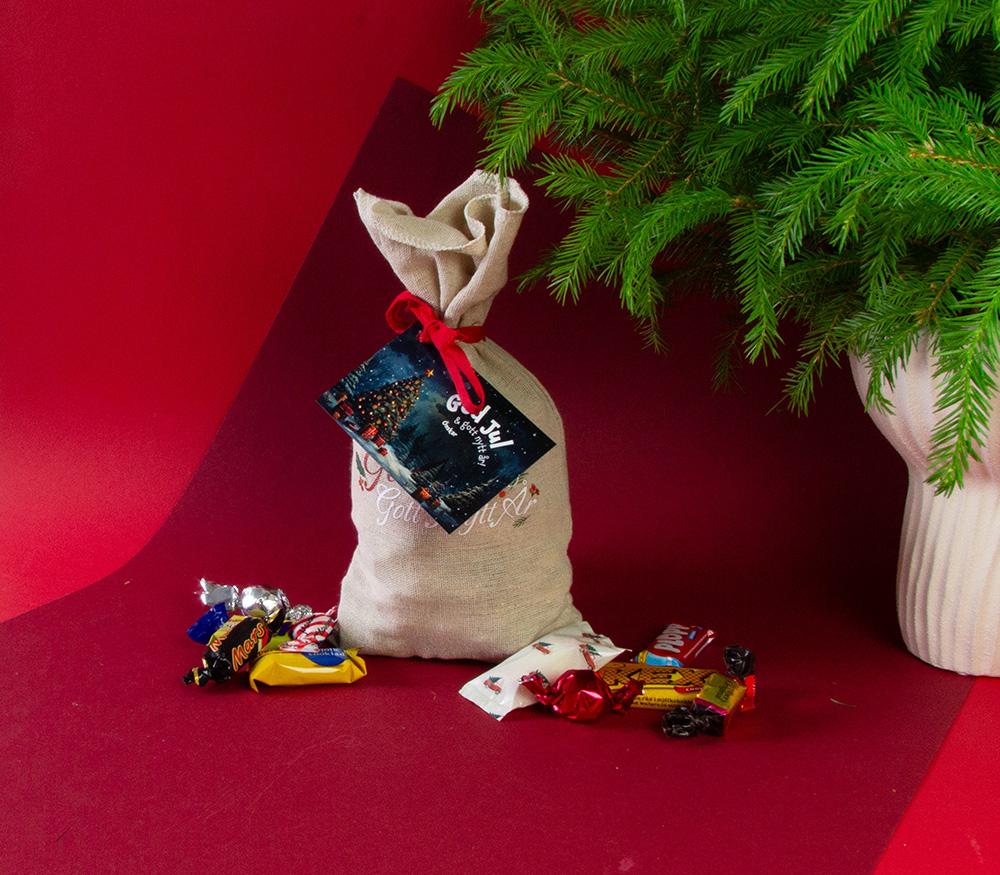 Klassisk julsäck med inslaget varumärkesgodis och julkort fäst med rött band
