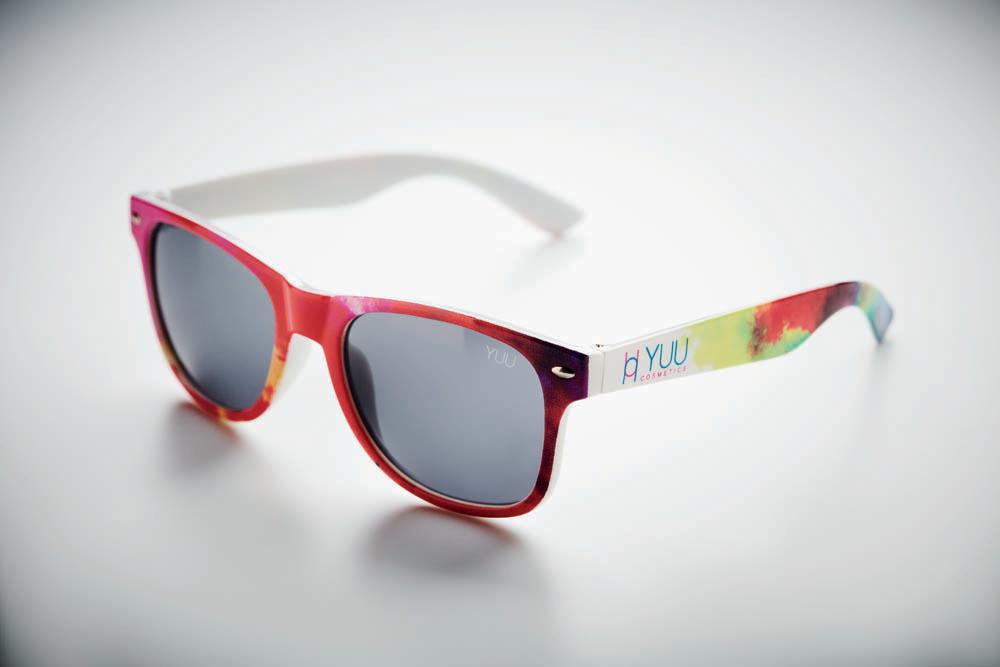 Solglasögon Tuv – fullfärgstryckt båge med logotyp på skalm Solglasögon Tuv med vit skalm och fullfärgstryckt båge i rosa/lila mönster samt logotyptryck på skalm (sned vy)