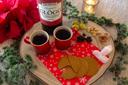 Upphälld glögg med pepparkakor, mandlar, russin och skumtomtar på en juldekorerad bricka