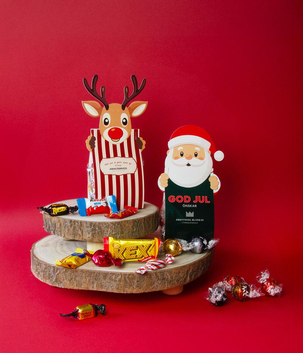 Julgodis i cellofanpåse med ren- och tomtefigur Cellofanpåsar med julgodis i ren- och tomteform på röd bakgrund